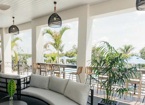 a living room with a white couch and a balcony with palm trees
