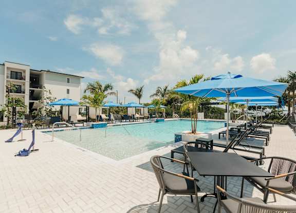 a swimming pool with tables and umbrellas