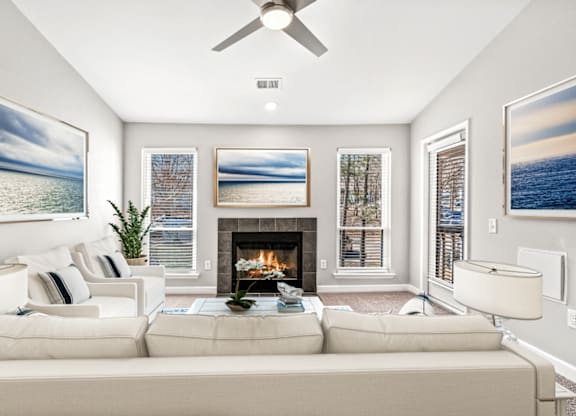 A living room with a fireplace and a painting of a beach scene on the wall at Paces Pointe Apartment Homes, North Carolina