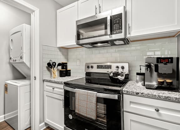 A kitchen with white cabinets and black appliances at Paces Pointe Apartment Homes, North Carolina
