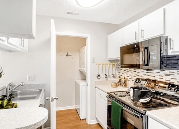A kitchen with a stove, sink, and cabinets at Paces Pointe Apartment Homes, Matthews, 28105