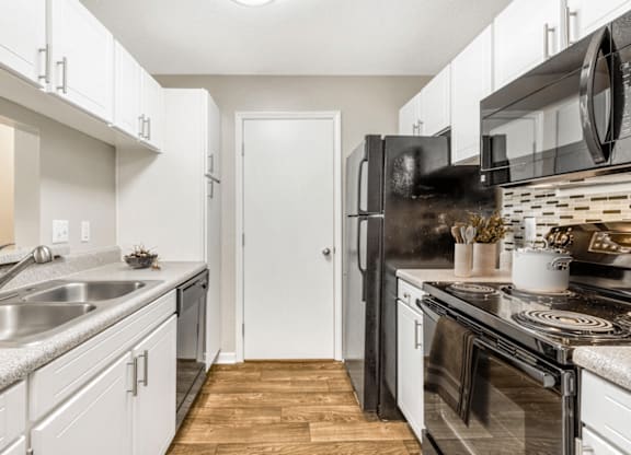 A kitchen with a black refrigerator and white cabinets at Paces Pointe Apartment Homes, Matthews, North Carolina