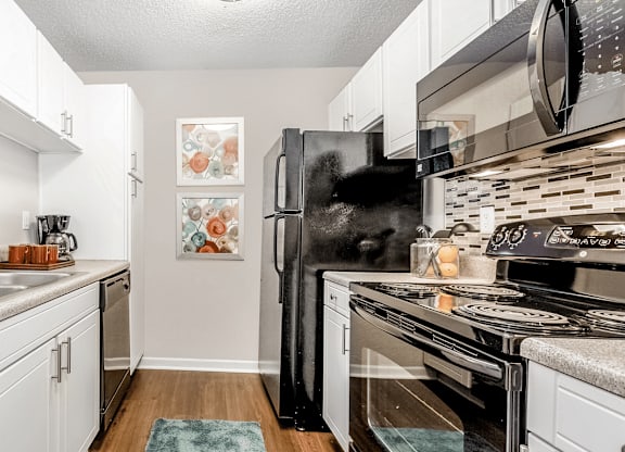 A kitchen with white cabinets and a black refrigerator at Paces Pointe Apartment Homes, North Carolina, 28105