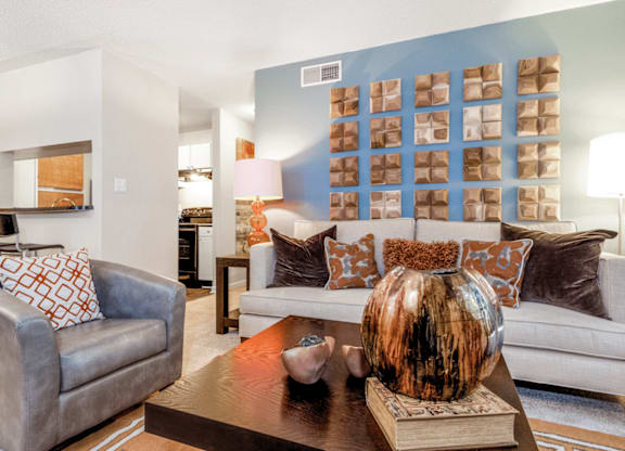 A living room with a grey couch, a brown coffee table, and a white sofa at Paces Pointe Apartment Homes, Matthews