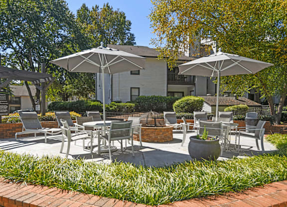 A patio with chairs and umbrellas is surrounded by green plants at Paces Pointe Apartment Homes, North Carolina, 28105