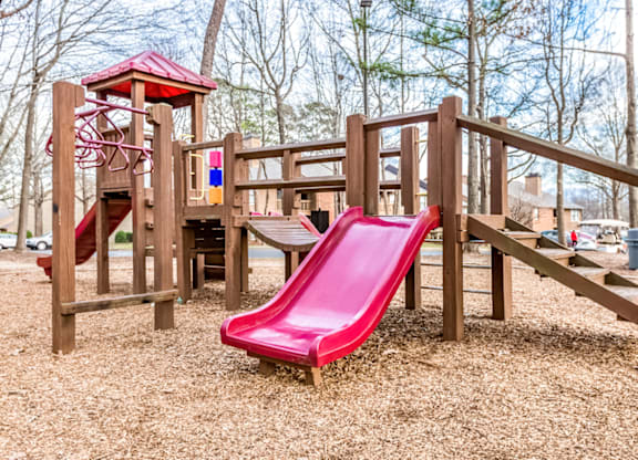 A playground with a red slide and wooden structure at Paces Pointe Apartment Homes, North Carolina, 28105