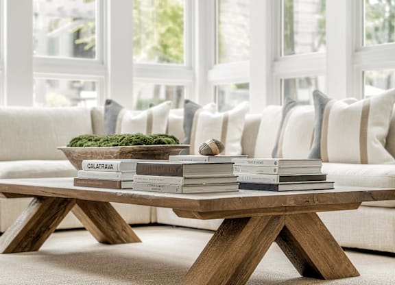 A coffee table with a stack of books on top of it in front of a white couch at Paces Pointe Apartment Homes, North Carolina, 28105