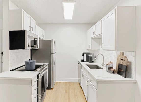 a kitchen with white cabinets and white appliances at The Parke at Trinity Apartment Homes, Raleigh, NC, 27607