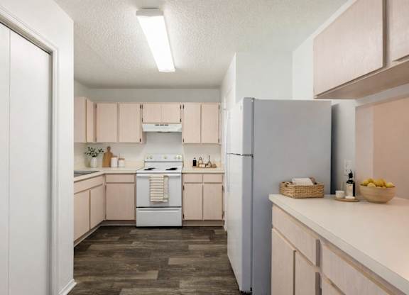 A kitchen with a white refrigerator and wooden floors.