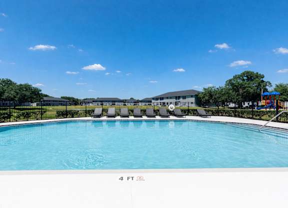 A swimming pool with a blue sky and clouds in the background.
