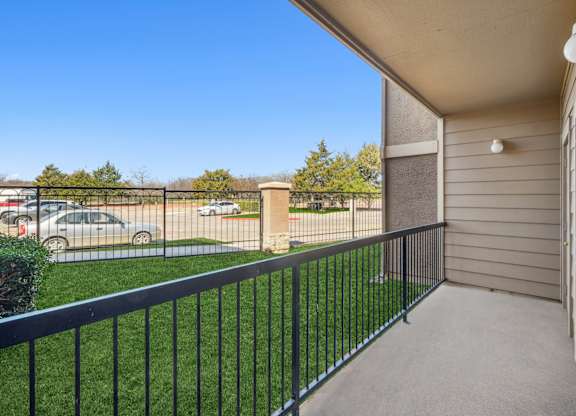 A balcony with a black railing overlooking a parking lot.