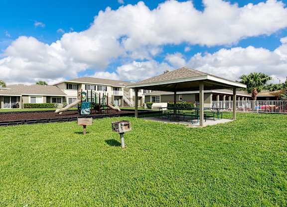 A large grassy area in front of a building with a playground.
