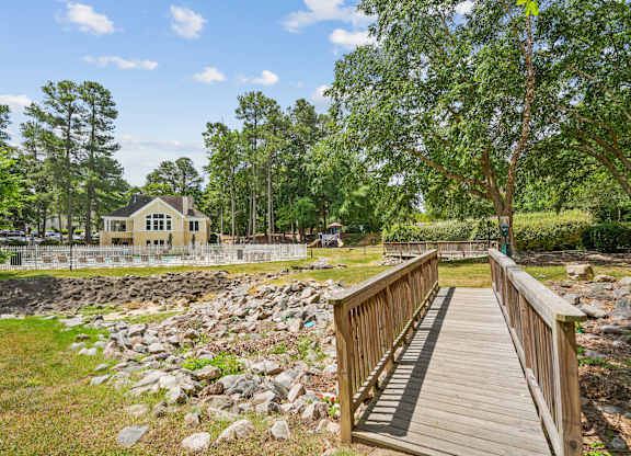 A wooden bridge leads to a house surrounded by trees at Regency Park Apartment Homes, Raleigh