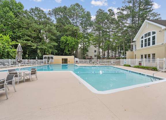 A large outdoor swimming pool surrounded by a fence and trees at Regency Park Apartment Homes, Raleigh, NC, 27616