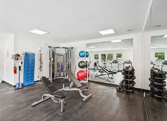 A gym with a variety of equipment including weights and a bench at Regency Park Apartment Homes, Raleigh, NC, 27616