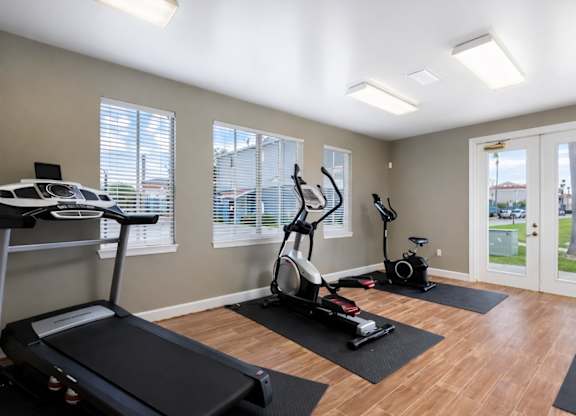 A home gym with a treadmill, elliptical trainer, and stationary bike.
