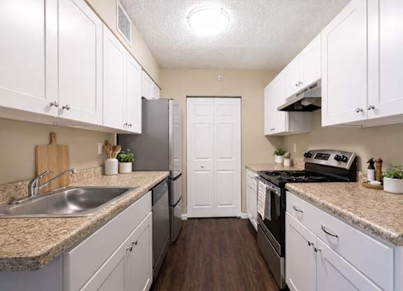 A kitchen with white cabinets and a granite countertop.