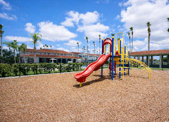 A playground with a red slide and yellow and blue play structures.