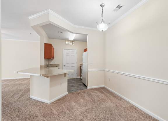 A room with a kitchenette and a doorway leading to another room.