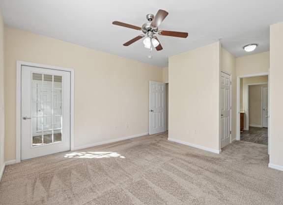 A room with a ceiling fan and carpeted floor.