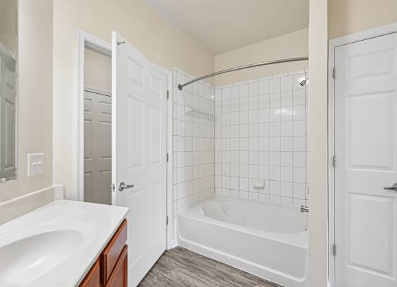 A white bathroom with a tub, sink, and shower.