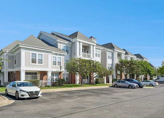 A row of townhouses with cars parked in front.