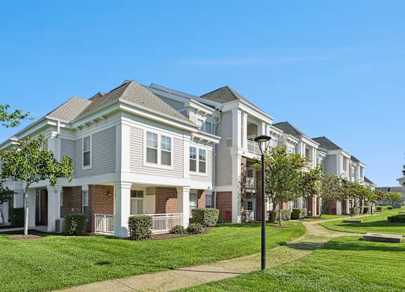 A row of townhouses with green lawns in front.