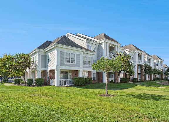 A row of white houses with green lawns in front.