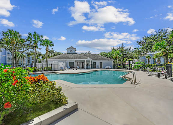 Pool area with tanning chairs on the deck surrounded by natural landscaping