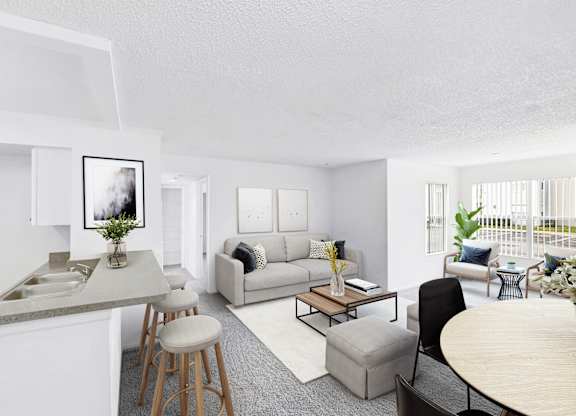 Interior of apartment from kitchen area facing the living room couch and dining room table