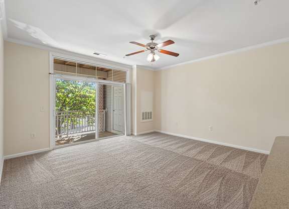 A room with a carpeted floor and a ceiling fan.