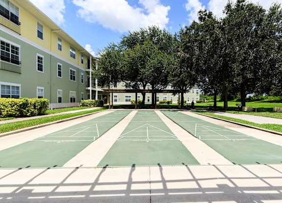 A tennis court is surrounded by apartment buildings.