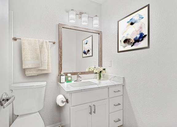 A white bathroom with a towel hanging on the towel rack.