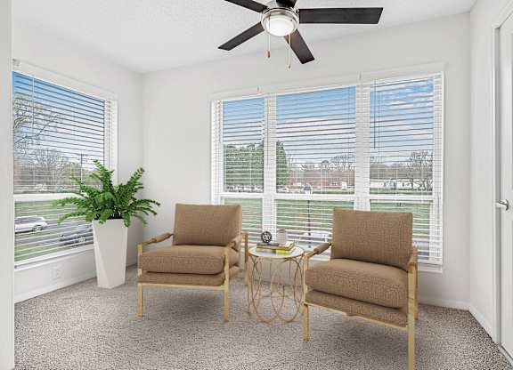 A room with two chairs and a table in front of a window with blinds.