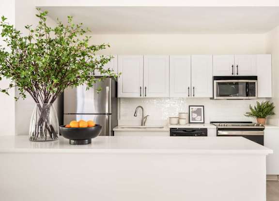 A kitchen with white cabinets and a white countertop.