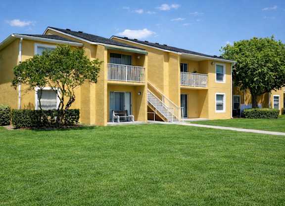 A yellow apartment building with a green lawn in front.