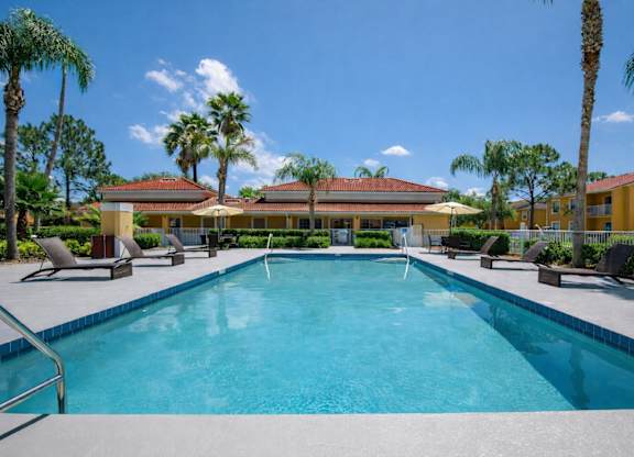 A swimming pool surrounded by palm trees and lounge chairs.