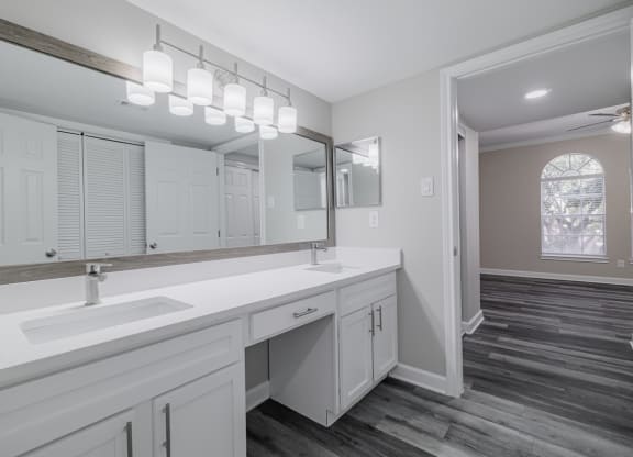 bathroom with dual vanities, white countertops and cabinetry