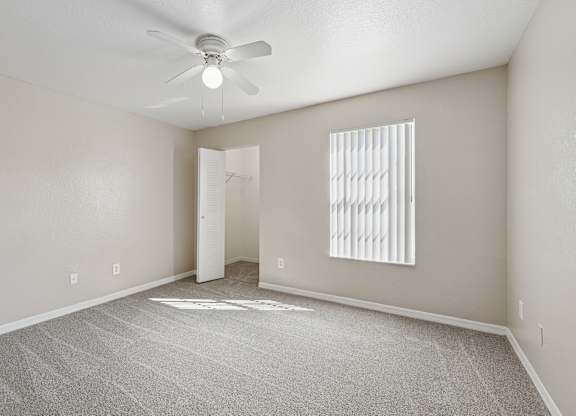 A room with a ceiling fan and a window with blinds.