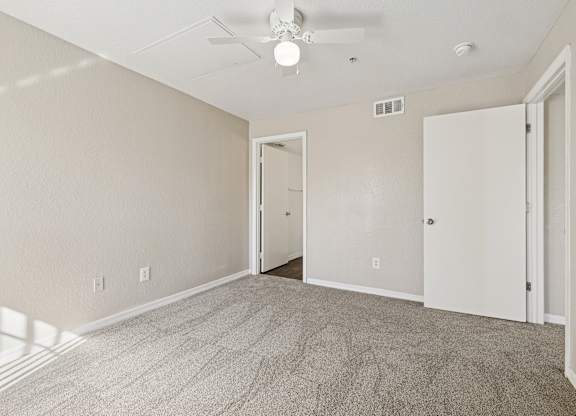 A room with a carpeted floor and a ceiling fan.