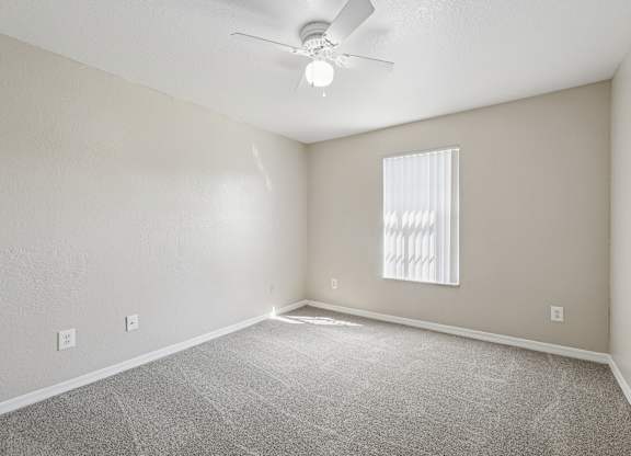 A room with a ceiling fan and a window with blinds.
