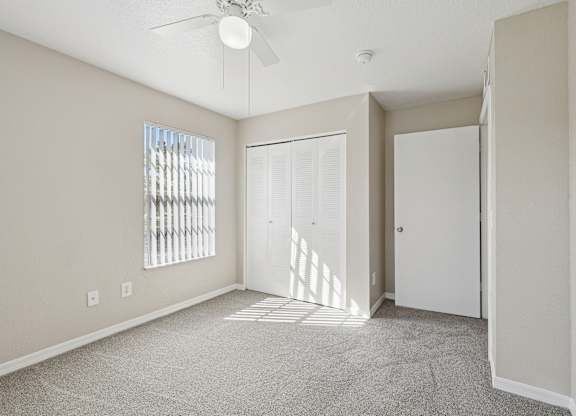 A room with a ceiling fan and a window with blinds.