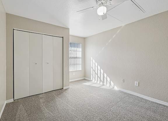 A room with a ceiling fan and a window with blinds.