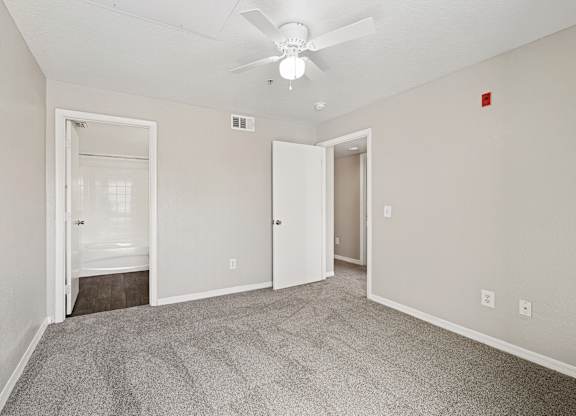 A room with a carpeted floor and a ceiling fan.