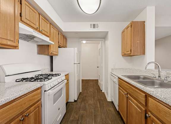 A kitchen with white appliances and wooden cabinets.