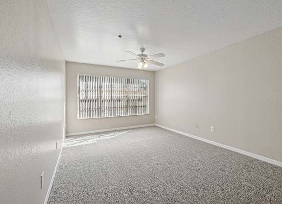 A room with a ceiling fan and a window with blinds.