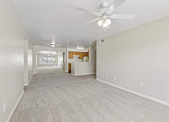 A spacious room with a ceiling fan and carpeted floor.