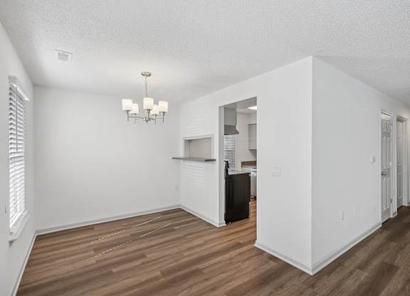 A white room with wood flooring and a chandelier.