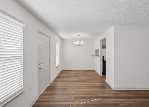 A long, empty hallway with white walls and wood flooring.