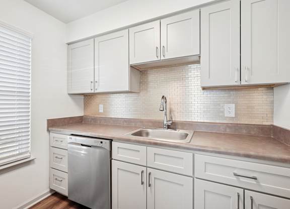 A kitchen with white cabinets and a tiled backsplash.
